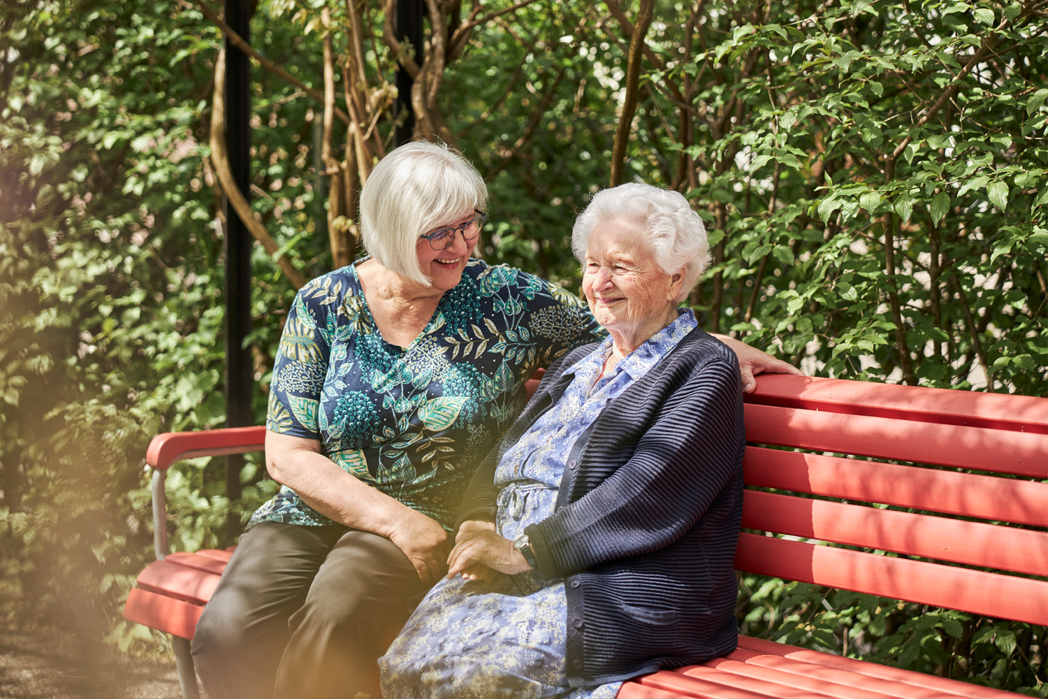 Frauen auf roter Bank im Grünen